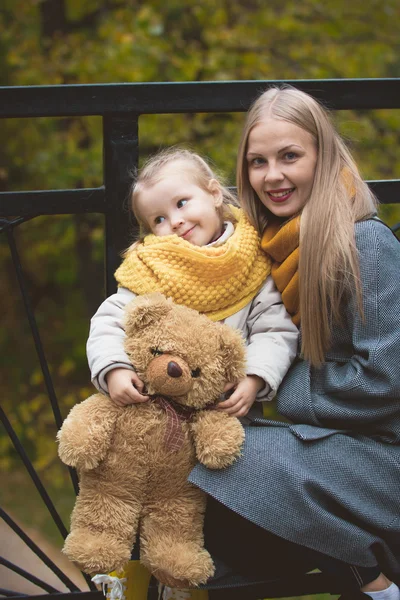 Matka, její dcera a hračka Teddy, který pózujte a kráčí v podzimním parku, zblízka — Stock fotografie