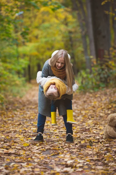 Šťastná rodinka v podzimní parku-matka si hrála se svou dcerou mezi žlutými listy — Stock fotografie