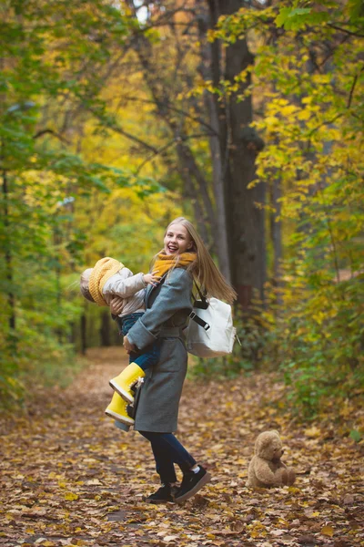 Šťastná rodina se baví v podzimní parku-matka si zahrává se svou dcerou mezi žlutými listy — Stock fotografie