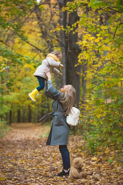 La familia feliz se divierten paseando en el parque otoñal - La madre da la hija rubia lanza — Foto de Stock