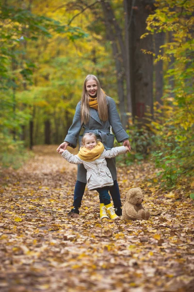 Madre e hija pequeña rubia sonriendo posando en el parque de otoño, vidas amarillas alrededor — Foto de Stock