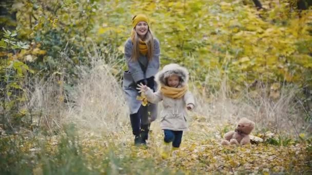 Moeder en haar dochter meisje lopen in een herfst park - kind uitgevoerd, slow-motion — Stockvideo