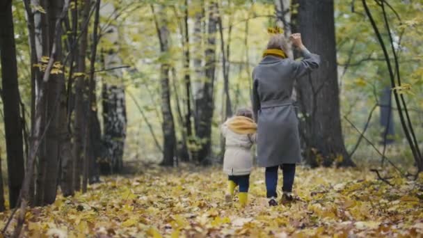 Mère et sa fille petite fille jouant dans un parc d'automne - maman et son enfant s'amusent et marchent 