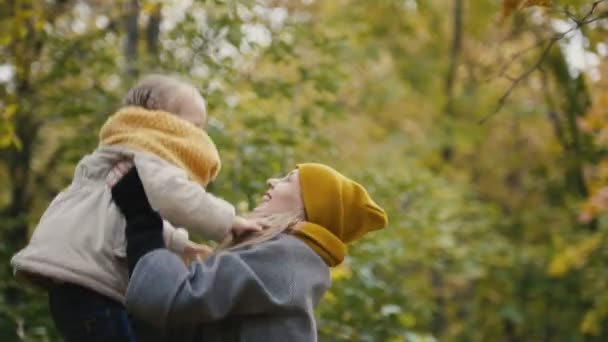 Mère et sa fille petite fille jouant dans un parc d'automne - maman jette un enfant 