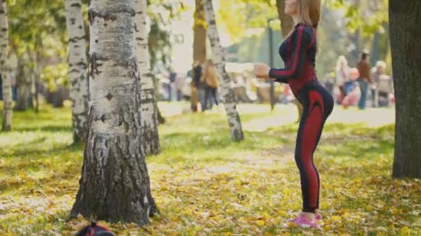Seksowny atrakcyjny blond bikini-fitness kobiece model rozciągający się w parku jesień na ziemi pokryte żółte liście - ćwiczenia o brzoza — Wideo stockowe