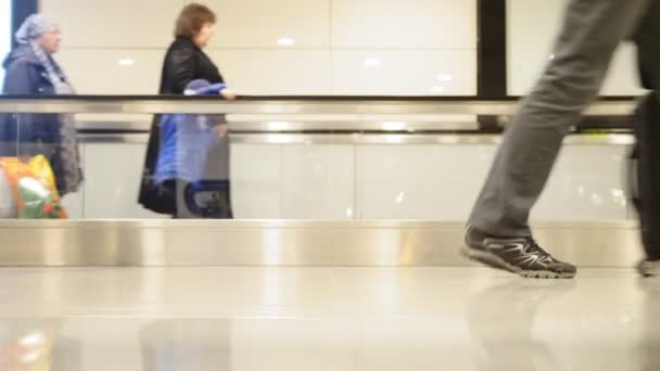 Personas caminando por escaleras móviles con equipaje en el aeropuerto internacional, tiro de cerca de piernas y zapatos — Vídeos de Stock