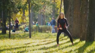 Fitness kadın vücut geliştirme egzersiz güneşli sonbahar Parkı'nda yapıyor. Onun vücut - ağız kavgası yaparken uygun beyaz sportif kız