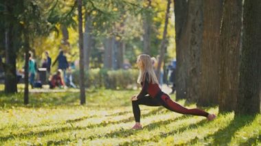 Fitness kadın vücut geliştirme egzersiz güneşli sonbahar Parkı'nda yapıyor. Uygun beyaz sportif kız onun vücut