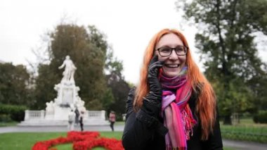 Kızıl saçlı ve gözlüklü duygusal park - Burggarten, Viyana'da telefonda konuşurken ile genç ve güzel kadın