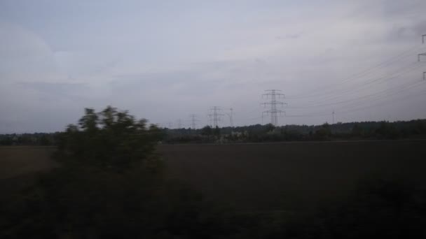 View from train - High voltage tower, meadows, wind energy turbine — Stock Video