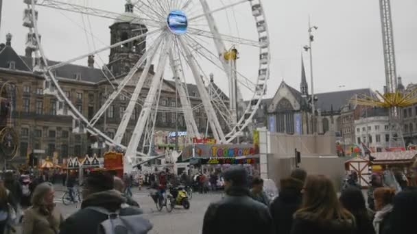 AMSTERDAM, NETHERLANDS - 16 oct 2016, Dam Square - historical center of Holland CAPITAL, tourists, bicycle and cars on the street, View with amusement Park - Ferris wheel, telephoto — Stock video