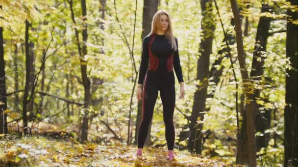 Vrouw doet fitness oefeningen buiten. Vrouw haar ellebogen in herfst bos uitrekken. Slim meisje op outdoor training — Stockvideo