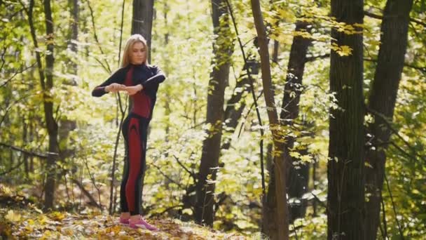 Vrouw doet fitness oefeningen buiten. Vrouw die zich uitstrekt in herfst bos. Slim meisje op outdoor training, slow-motion — Stockvideo