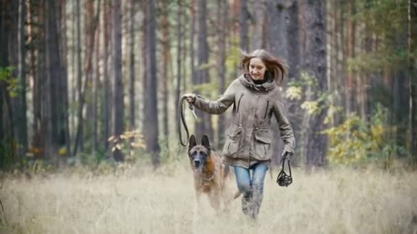 Joven linda mujer feliz juega con su perro - pastor alemán en el parque amarillo de otoño - el perro corre en la hierba y jugar con la correa, cámara lenta — Vídeos de Stock