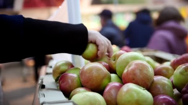 Supermercado - mão de clientes selecionar maçãs no departamento de frutas, desfocado — Vídeo de Stock