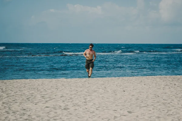 Молодой человек бегает по пляжу на тропическом курорте — стоковое фото