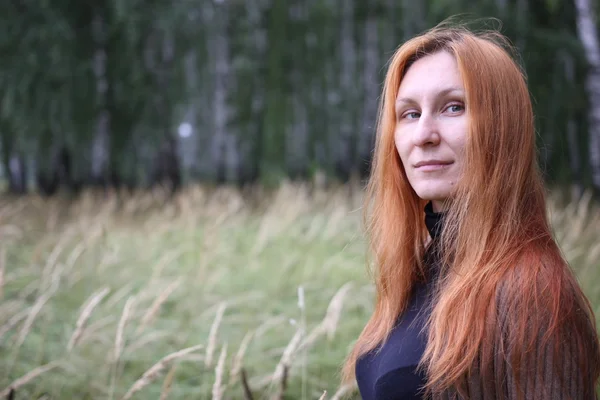 Привлекательная женщина с рыжими волосами в осеннем лесу — стоковое фото
