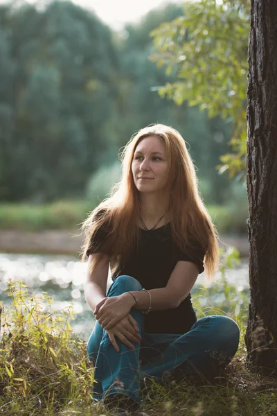 Молодая привлекательная женщина, сидящая у лесной реки, Россия, Сибирь — стоковое фото