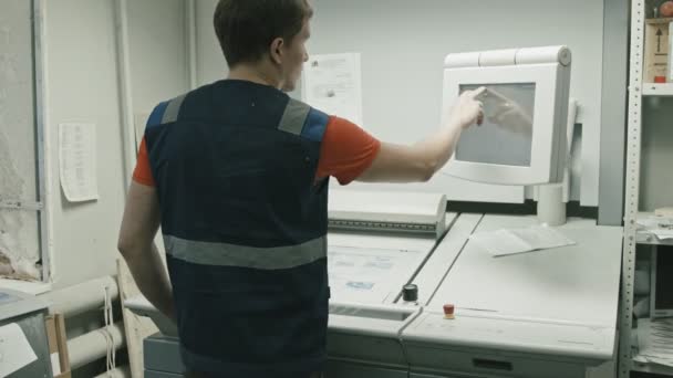 Полиграфическая промышленность - работник использует сенсорный монитор для печатного процесса, вид сзади — стоковое видео