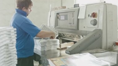 Mavi ceket çalışan işçi koyar kağıt kesici Giyotin makinedeki yazdırma bir fabrikada, kaymak