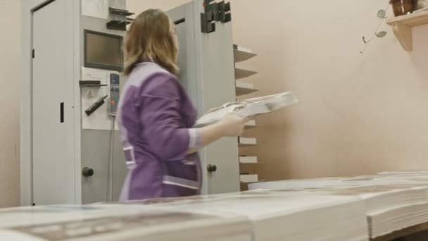 Vrouw plaatst een vel papier voor de voltooiing van het tijdschrift op polygraaf machine in de drukkerij — Stockvideo