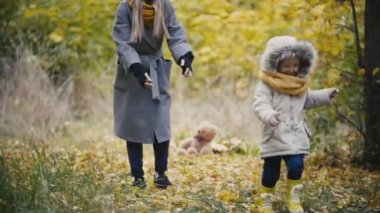 Genç kız - küçük kızı güler ve yakalamak sonbahar park, ağır çekim annesi ile çalış