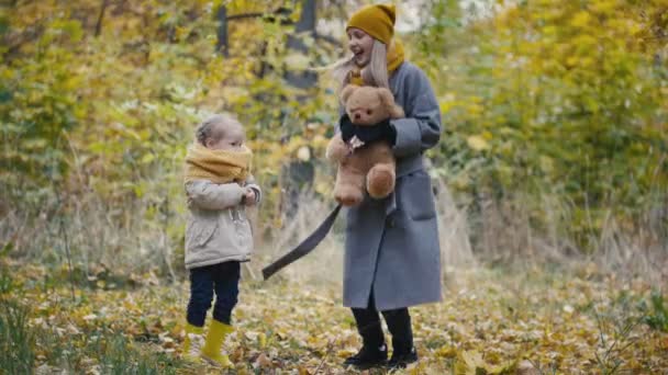 Concept familial sain - petite fille blonde avec sa maman passer du temps dans le parc d'automne - sauter et s'amuser — Video