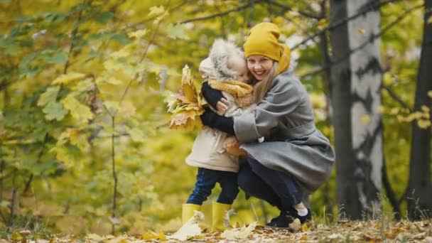 Красавица маленькая дочка с мамой гуляет в осеннем парке - обнимается — стоковое видео