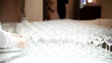 Garson çok boş bardak beyaz masa örtüsü koyar.