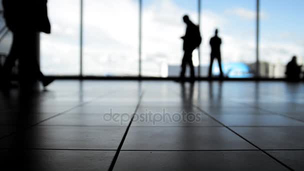 Los pasajeros siguen al embarque con el equipaje delante de la ventana en el aeropuerto, silueta — Vídeo de stock
