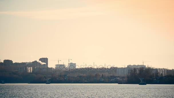 Stad landschap met rivier en huis in aanbouw bij zonsondergang — Stockvideo