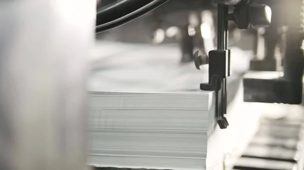 Друковані аркуші паперу подаються у друкарському верстаті. Зсув, CMYK — стокове фото