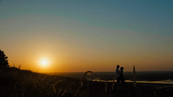 Älskande par - modig ung och vacker flicka på sunset silhouette, vidvinkel — Stockfoto