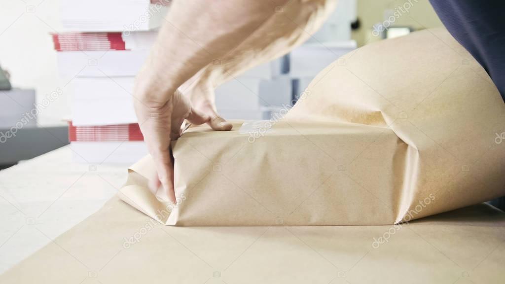 Close up mans hands packing boxes of sellotape in printing industry