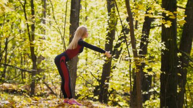 Eğitim egzersiz sahip kız sonbahar parkta. Seksi fitness-bikini sarışın model kırmızı takım elbise ve pembe spor ayakkabı