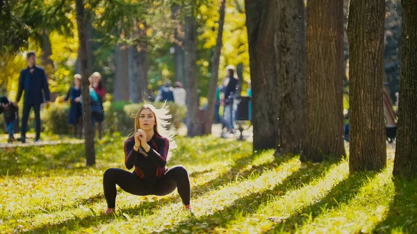 Joven modelo femenino de fitness Ejercicio en un prado en el parque de otoño, Deportes Concepto de actividades al aire libre - sentadillas —  Fotos de Stock
