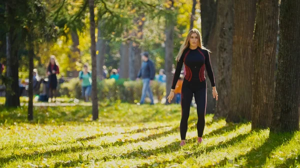 Fitness žena silový trénink dělá cvičení na slunné podzimní park. Přizpůsobit kavkazské sportovní dívka výkonu její tělo - dřepy — Stock fotografie