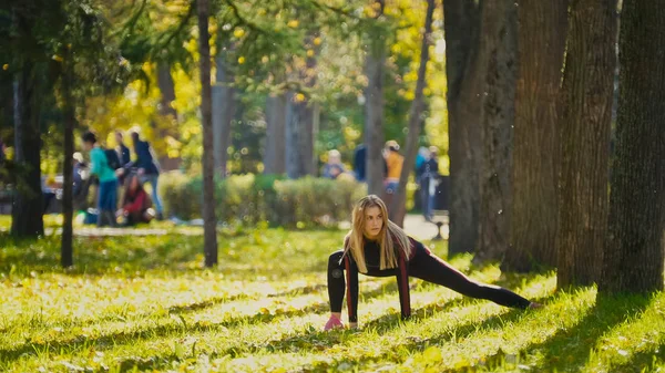 Kvinnan styrka konditionsträning gör träning på soliga höst park. Fit kaukasiska sportig tjej tränar sin kropp — Stockfoto