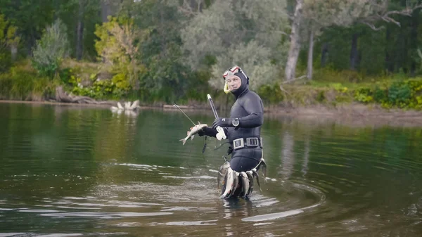 Lanza pescador muestra peces de agua dulce en después de la caza en el río bosque — Foto de Stock