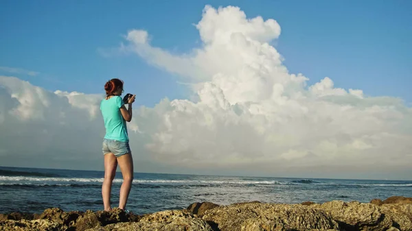 Giovane donna con i capelli rossi in occhiali fotografie mare in piedi sugli scogli, spiaggia della Repubblica Dominicana — Foto Stock