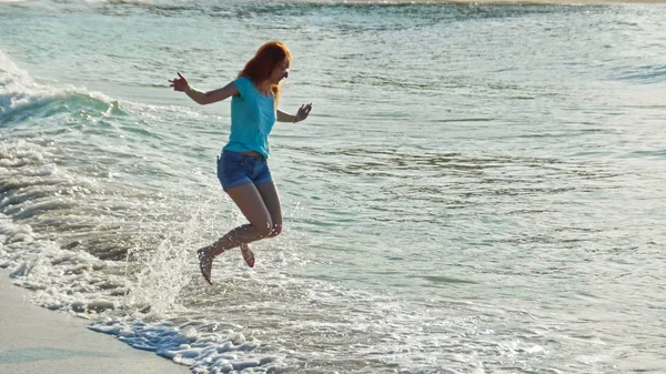 Giovane donna dai lunghi capelli rossi gioca le onde correndo, sentendo il mare, spiaggia di mare della Repubblica Dominicana — Foto Stock