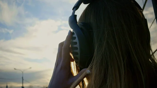 Menina bonito em fones de ouvido no parque ao pôr do sol. de perto — Fotografia de Stock