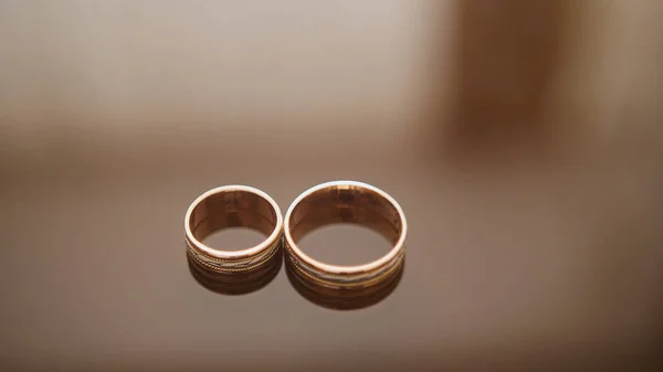 Anéis de casamento dourados na mesa de óculos de espelho - um está perto do outro, macro — Fotografia de Stock