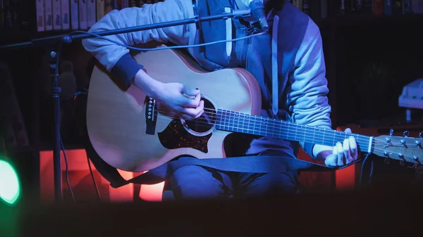 Κιθαρίστας παίζει ακουστική κιθάρα και τραγουδά μικρόφωνο σε νυχτερινά κλαμπ, μπλε φώτα, εσωτερικη — Φωτογραφία Αρχείου