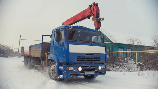 Camión de construcción en pueblo de invierno cubierto de nieve en día soleado — Foto de Stock