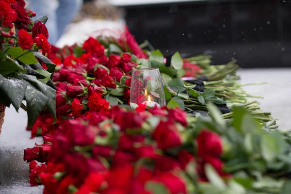 Nejlika blommor symbol för sorg - ljus i vinden och röda blomman på monumentet — Stockfoto