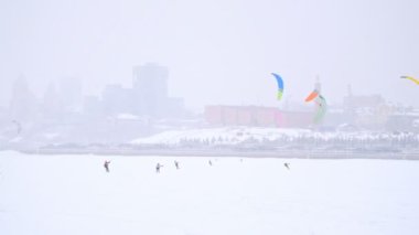 Kış extremal spor - kar-uçurtma sportsmens bir sürü buz Nehri üzerinde blizzard bulutlu gün sürmek