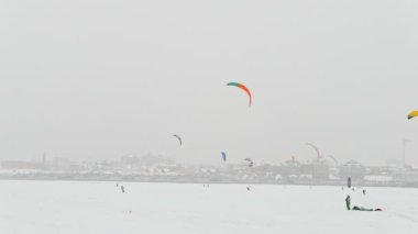 Kış extremal spor - colorul kar-uçurtma blizzard bulutlu gün City'de önünde buz Nehri üzerinde