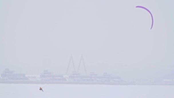 Deportistas de kite de nieve deslizándose sobre el lago de hielo - deporte extremo de invierno en ventisca — Vídeo de stock