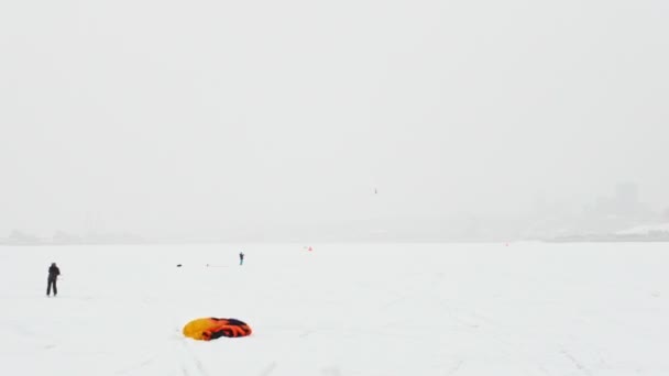 Snow-kite sportsmen on the ice river - winter extremal sport at blizzard — Stock Video